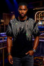 Man wearing a black t-shirt with silver embellishments in a bar setting