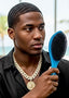 Man holding a blue hairbrush with a blurred outdoor background