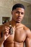 Man holding a bottle of hair oil in a bathroom setting