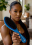 Woman holding a blue hairbrush with 'Slydes' branding in a blurred indoor setting
