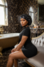 Woman in a black dress sitting on a white chair in a luxurious bathroom.