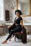 Woman in black athletic wear sitting on a chair in a bathroom with marble walls and gold accents.
