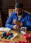 Man in a blue shirt sitting at a table with grooming tools and books.