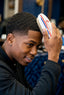 Man brushing his hair with a red, white, and blue brush against a blurred background