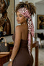 Woman wearing a leopard print headscarf in an indoor setting with art on the wall.