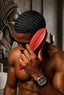 Man with a headwrap using a wooden brush in a room with decorative elements.