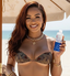 Woman in a bikini holding a skincare product on a beach