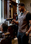 Barber using a hair dryer on a customer in a barbershop.