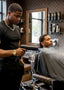 Barber using a hair dryer on a customer in a barbershop.