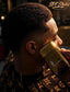 A man in a barber cape receives a hot air style on his head with a gold SPI Styles lighter. The image features warm, moody lighting and has 'SPI Styles' branding in the top right corner.