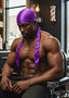 Muscular man with a purple headscarf sitting in a barber shop chair.