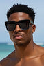 Man wearing sunglasses with a clear blue sky and ocean background