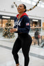 Woman in a navy sweatshirt with 'USA' and black leggings standing in a shopping mall.