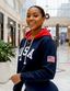 Woman wearing a navy hoodie with 'USA' and an American flag patch in a snowy mall setting.