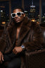 Man wearing a fur coat and sunglasses with a cityscape background