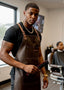 Barber wearing a brown apron holding a brush in a barbershop.