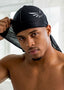 Man wearing a black headscarf with a logo, shirtless, against a neutral background